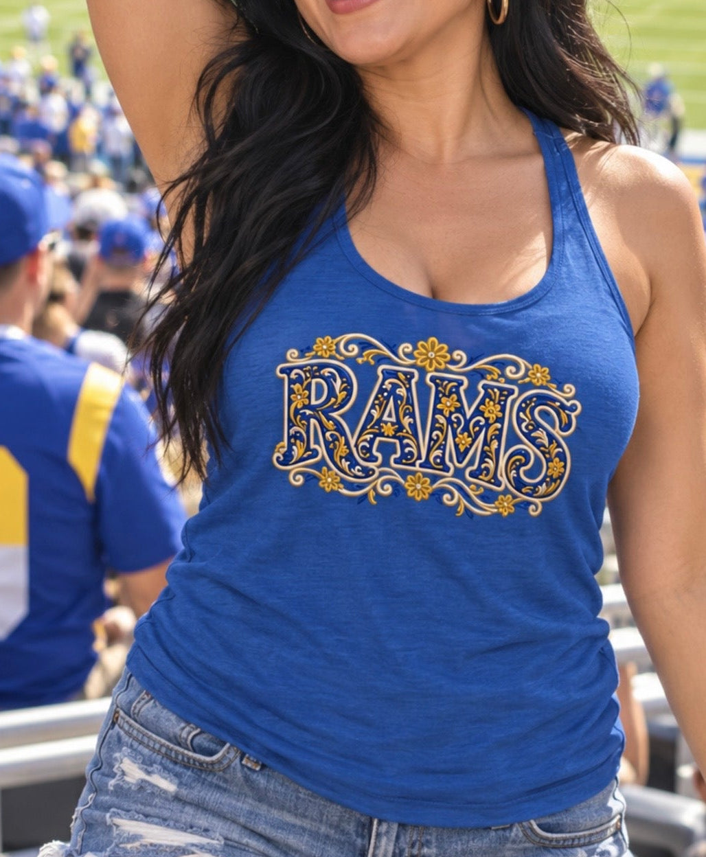A woman at a football stadium wearing a blue tank top with a gold and white 'RAMS' graphic, denim shorts, and sunglasses.